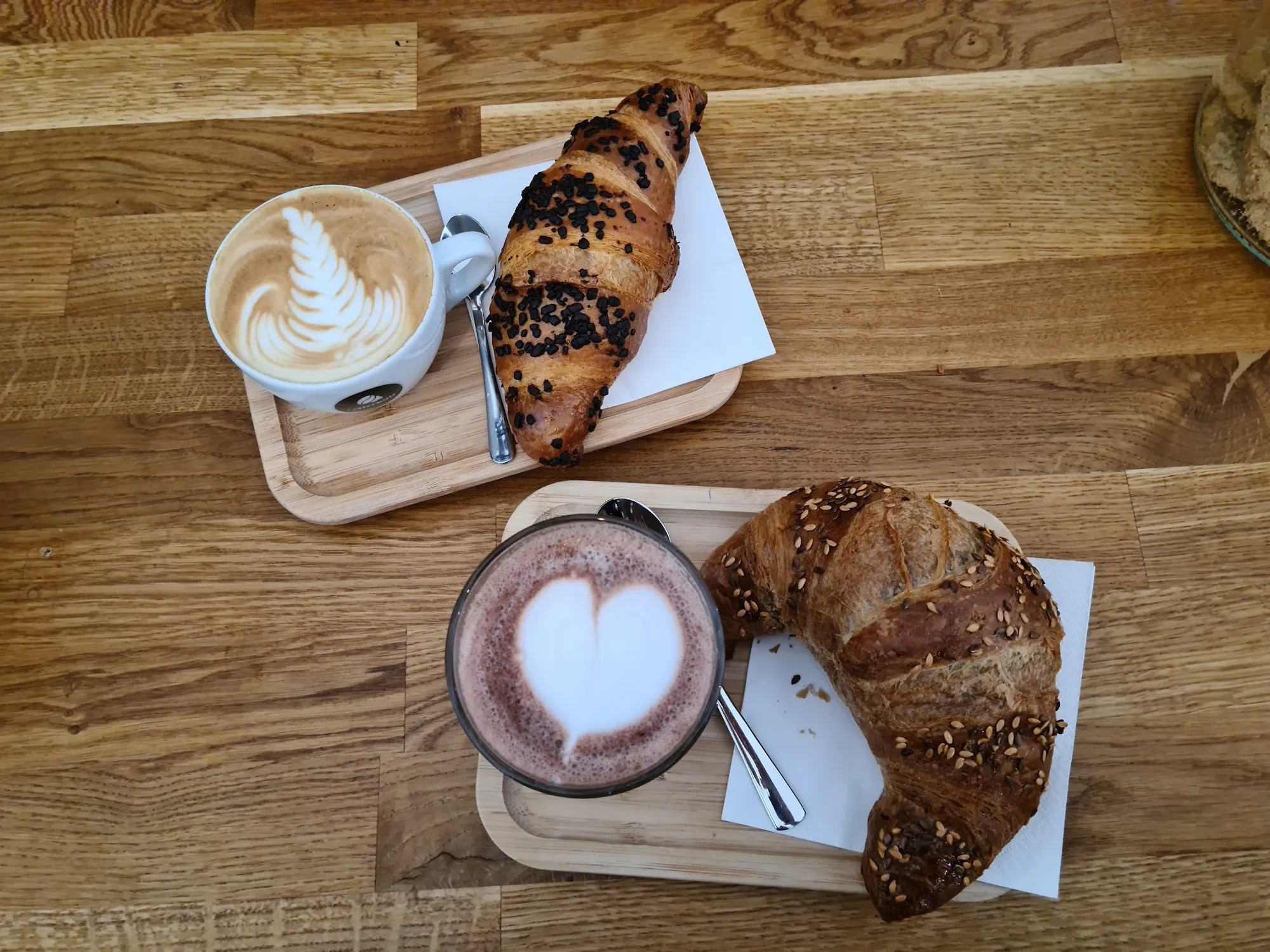 Cappuccino und heiße Schokolade mit Latte Art, dazu zwei Croissants, von oben