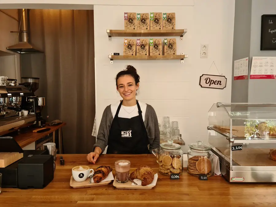 Barista an der Theke mit Kaffee und Croissants