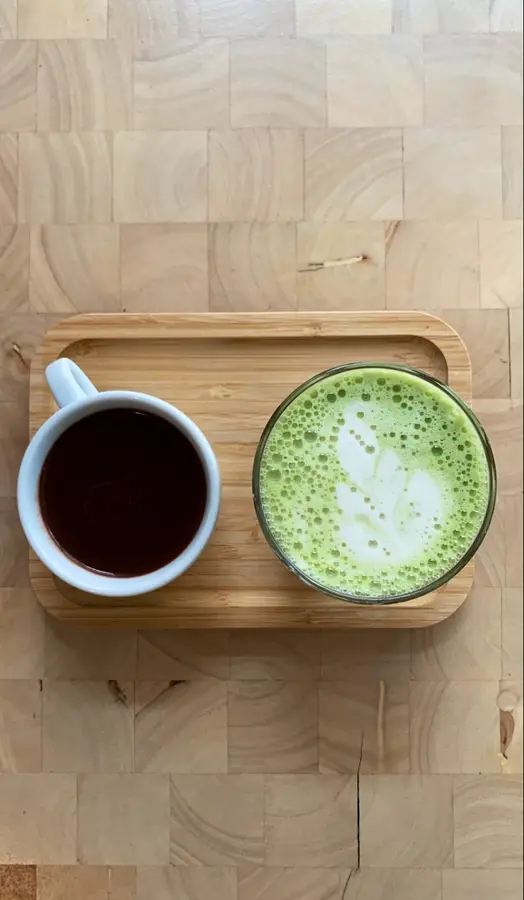 Schwarzer Kaffee und Matcha Latte nebeneinander auf einem Tablett